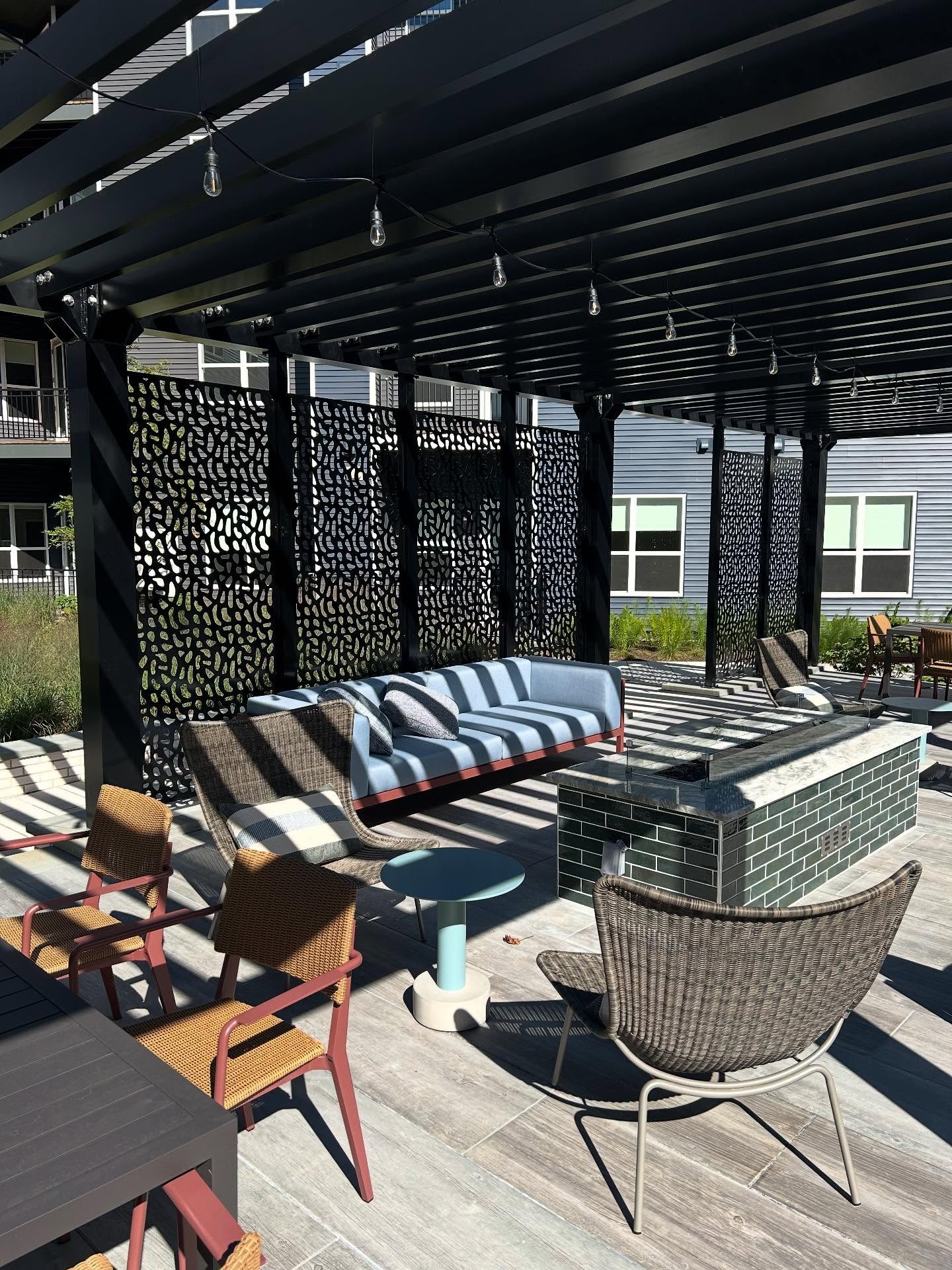 Dark pergola covering a landscaped backyard dining patio