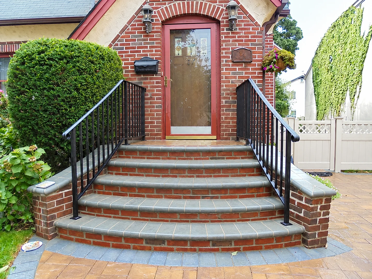 Black aluminum picket railings framing a curved brick residential front stair