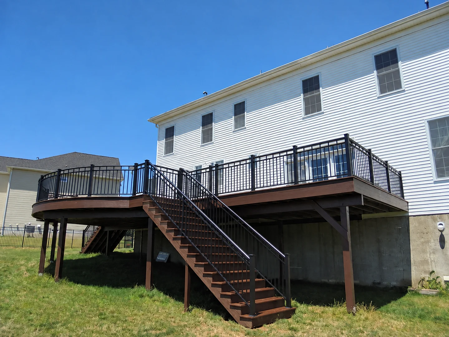Black aluminum picket railing around a curved residential deck with a central stair