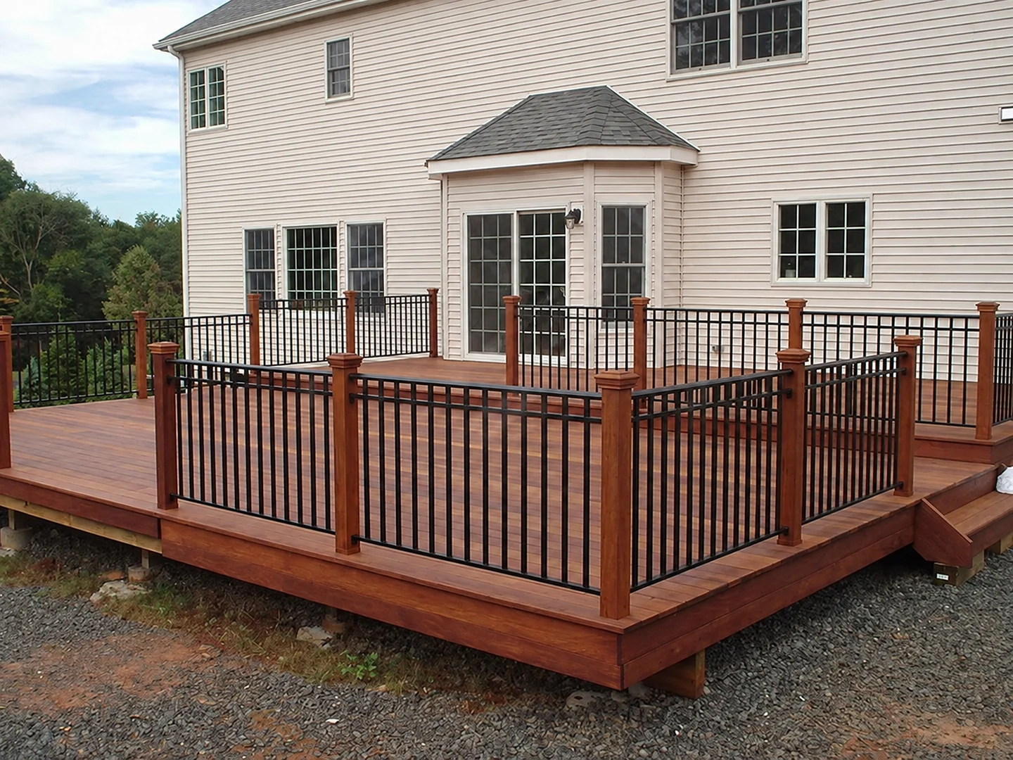 Black aluminum picket railing around a large residential wood deck with wood posts
