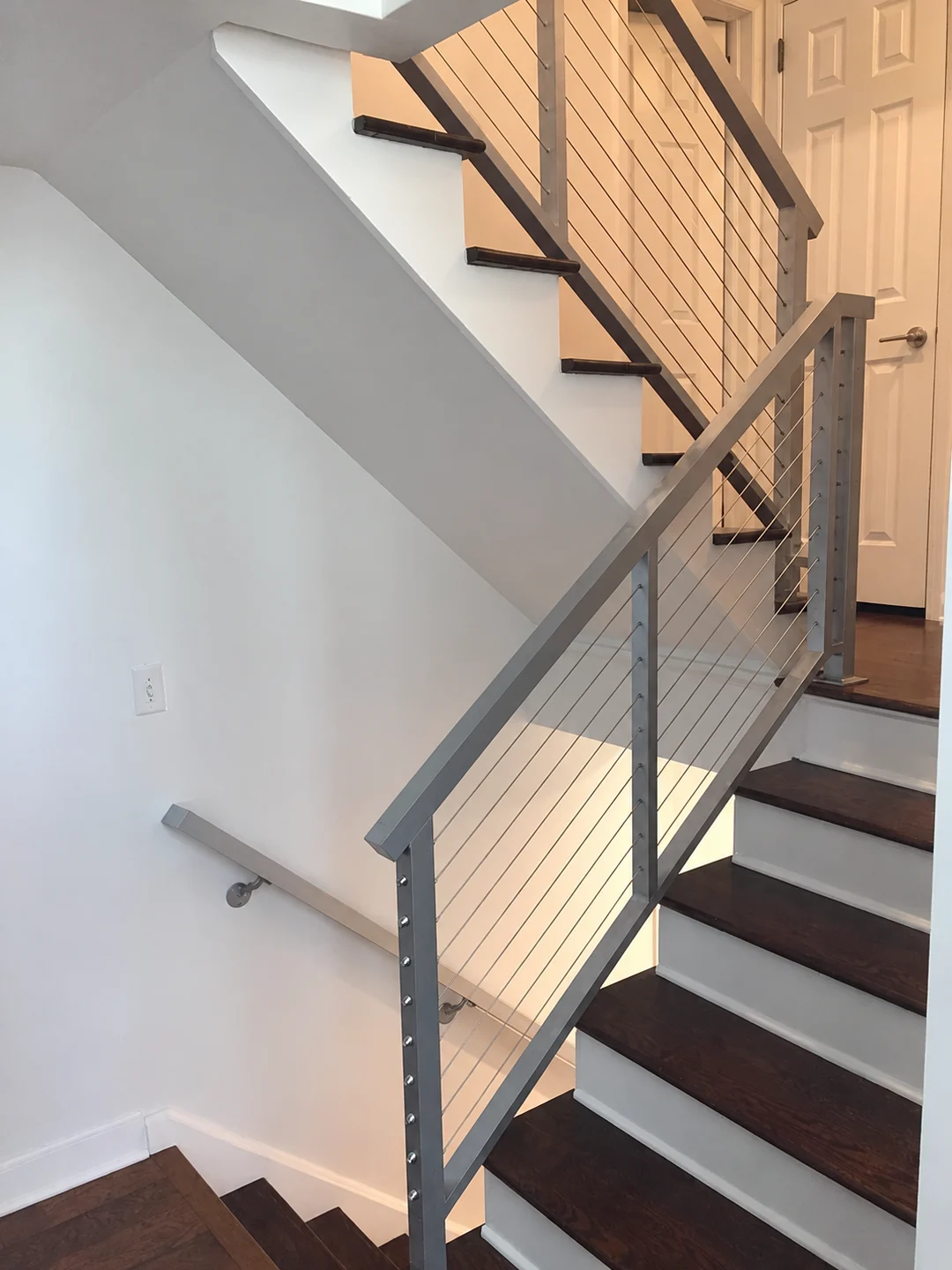 Dark cable railing with wood stair treads inside a residential stairwell