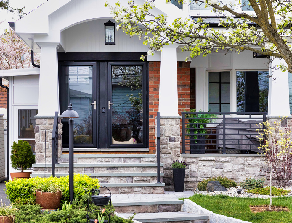 Custom black metal porch railing at a finished stone entry