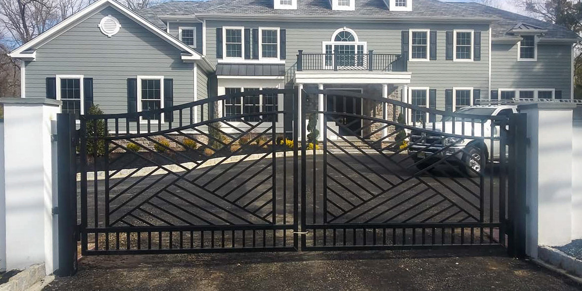 Black double driveway gate installed at the entrance to a gray residential home