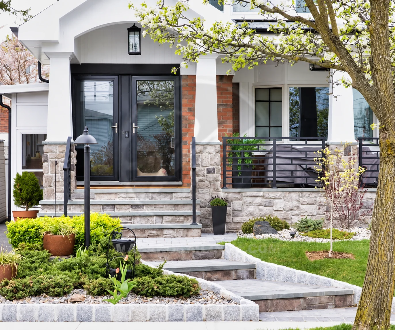 Black horizontal-picket porch railing beside a landscaped stone residential front entry